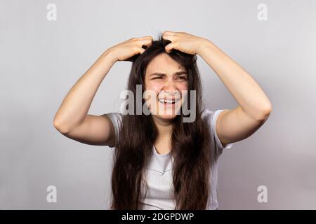 Das Mädchen kratzt ihren Kopf mit beiden Händen, juckende Kopfhaut wegen ansteckender Krankheit Läuse. Pedikulose beim Menschen. Stockfoto