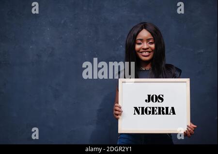 Afrikanische Frau halten weiße Tafel mit Jos Nigeria Inschrift. Bevölkerungsreichste Stadt in Afrika Konzept. Stockfoto