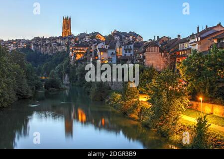 Fribourg, Schweiz von der Pont de millieu aus gesehen, die sich in der Nacht im Fluss Sarine spiegelt, mit dem Turm der St. Nicholas Kathedrale mit Blick auf Th Stockfoto