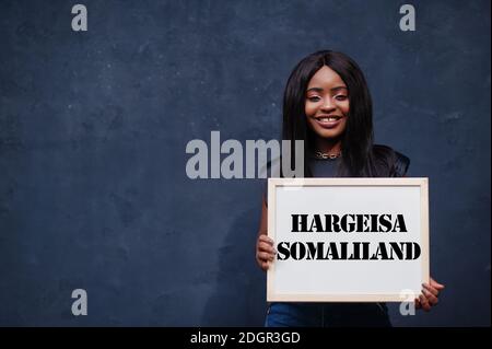 Afrikanische Frau halten weiße Tafel mit Hargeisa Somaliland Inschrift. Bevölkerungsreichste Stadt in Afrika Konzept. Stockfoto