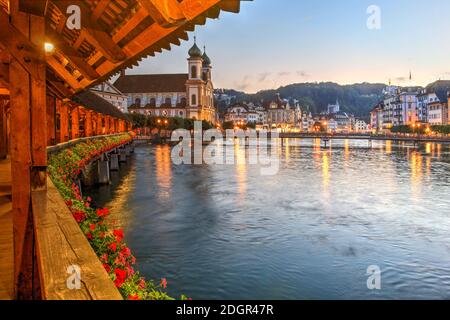 Abendszene von der malerischen Kapellenbrücke über den Reuss mit der Jesuitenkirche Luzern und dem Flussufer, Luzern, Schweiz. Stockfoto