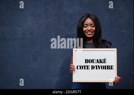 Afrikanische Frau halten weiße Tafel mit Bouake Cote d'Ivoire Inschrift. Bevölkerungsreichste Stadt in Afrika Konzept. Stockfoto