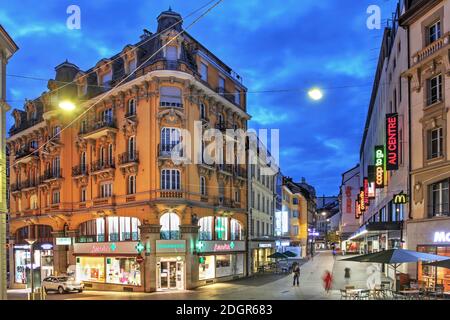 Nachtaufnahme entlang der Rue de St-Laurent, einer der Hauptverkehrsadern des Zentrums von Lausanne, Schweiz, von den Stufen der Kirche von St-Laurent aus. Stockfoto