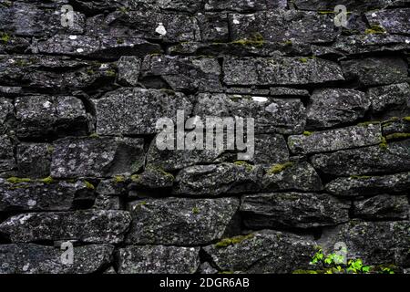 Mittelalterliche Steinmauer und Bogenarchitektur aus rauhen Granitfelsen. Nahaufnahme. Stockfoto