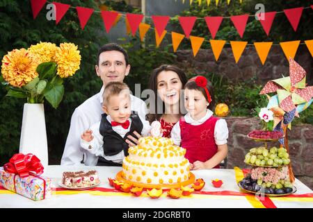 Familie von vier Personen Vater Mutter Sohn und Tochter feiert Geburtstag der Tochter drei Jahre sitzen auf einem festlich geschmückten Tisch Stockfoto