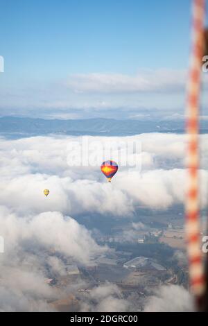 Bunte Heißluftballon in bewölktem Himmel vor Berge Stockfoto