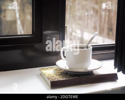 Eine Tasse Tee und ein Buch über die Fensterbank Stockfoto