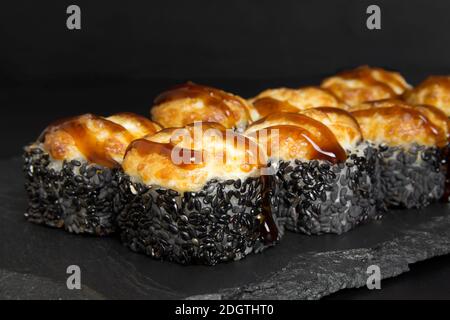 Sushi-Rollen mit Sesamsamen auf einem Steinbrett für Sushi Stockfoto