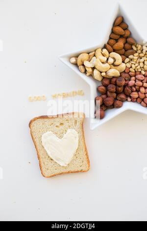 Sandwich zum Frühstück in Form von Herz mit Käse - Guten Morgen Inschrift Schüssel und mischen mit Nüssen Stockfoto