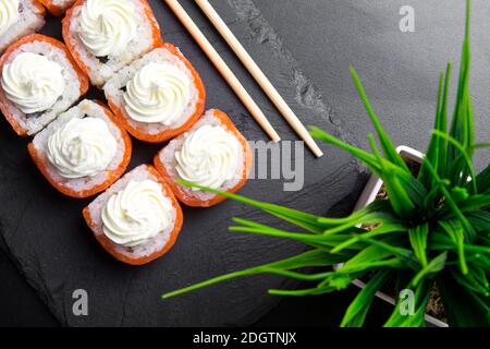 Sushi-Brötchen Philadelphia mit Lachs und gekrönt mit Frischkäse Stockfoto