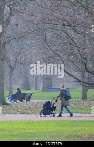 London, England, Großbritannien. Junge Mutter bei einem nebligen Tag im Green Park, Dezember 2020 Stockfoto