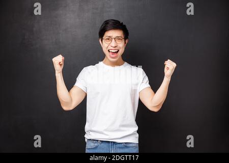 Glücklich erleichtert und zufrieden junge asiatische Kerl gratuliert seinem Team mit Sieg, Ziel erreichen, Hände wie Meister zu knümpen, feiern Stockfoto