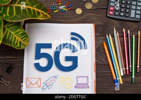 Notizbuch mit Notizen 5G auf dem Bürotisch mit Tools. Konzept mit Elementen der Infografiken. Stockfoto