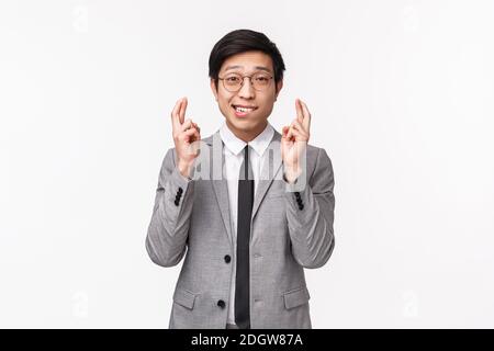 Waist-up-Porträt von niedlichen hoffnungsvollen asiatischen Mann, Büroleiter hoffen, zu erhöhen oder Förderung zu bekommen, Kreuzfinger viel Glück und Bissen Lippe Stockfoto