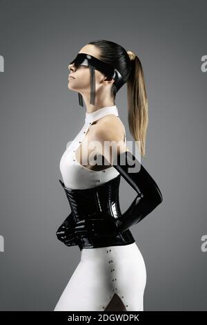 Futuristisches Porträt einer hübschen jungen Frau in einem weißen Kleid, trägt einen Hüftmiete, Handschuhe und ein schwarzes Latex-Stirnband Stockfoto