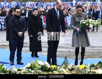 Der Herzog und die Herzogin von Cambridge, begleitet von Aiyawatt Srivaddhanaprabha (links), EINEM Familienmitglied des Leicester City Chairman Vichai Srivaddhanaprabha, legten während ihres Besuchs im King Power Stadium Blumen an der Tribute-Stelle nieder, um denen zu Tribut zu zollen, die beim Hubschrauberabsturz in Leicester City ihr Leben verloren haben Stockfoto