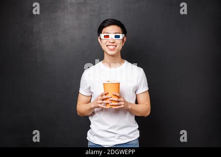 Freizeit, Filme und Lifestyle-Konzept. Gutaussehende fröhlich und aufgeregt asiatischen Mann in 3d-Brille, hält Popcorn und lächelnd amüsiert Stockfoto