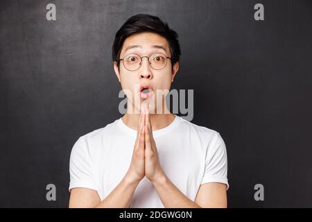 Nahaufnahme Porträt von amüsiert, enthusiastischen jungen asiatischen Mann halten die Hände im Gebet, Klammer Handflächen zusammen als Betteln für etwas, fragen Stockfoto