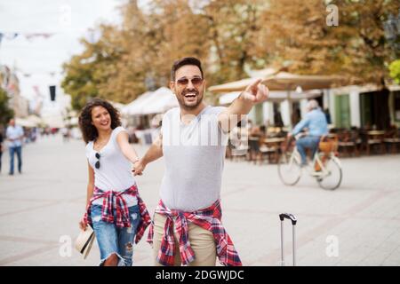 Handsome Mann führt seine wunderschöne junge Freundin an der Hand und zeigt etwas. Stockfoto