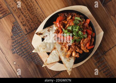 Fajitas mit Huhn und Paprika in einer Pfanne. Holzhintergrund. Stockfoto