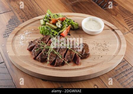 Top Blade Steak mit Salat und Sauce. Holzhintergrund Stockfoto