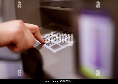 Nahaufnahme des Bildes einer weiblichen Hand mit schwarzen Nägeln, die die PIN-Nummer ihrer Karte am Geldautomaten eintippt. Stockfoto