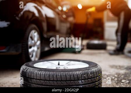 Neue Reifen auf dem Bürgersteig in der Nähe der Mechaniker bereit, den auf einem Auto zu ersetzen. Stockfoto