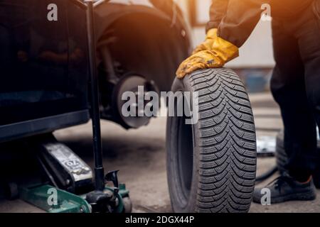 Automechaniker Mann mit elektrischer Schraubenzieher Reifenwechsel außerhalb. Car Service. Hände ersetzen Reifen auf Rädern. Reifenmontage Konzept. Stockfoto