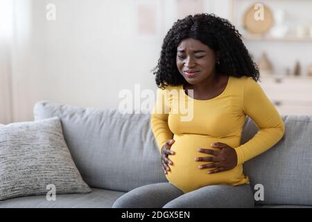 Schwarze schwangere Frau, die an Wehen zu Hause leidet Stockfoto