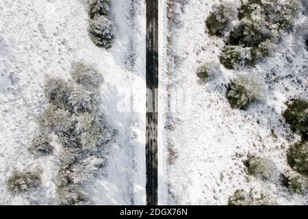 Luftaufnahme der leeren schneebedeckten Straße im Winterwald. Hochwertige Fotos. Stockfoto