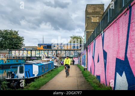 Ein Radfahrer auf dem Lea Valley Schleppturm, GBRf Güterzug, Hausboote, Street Art, Legacy Wharf, Stratford, East London, E15 2PN, Großbritannien Stockfoto