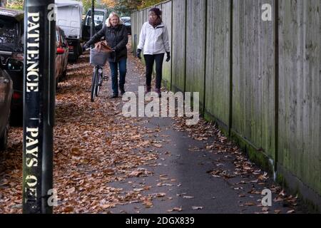 Street Art Sprichwort "Geduld zahlt sich aus" - und zwei Frauen auf einem öffentlichen Fußweg im Herbst, Coronavirus Lockdown 2020/1, Großbritannien Stockfoto