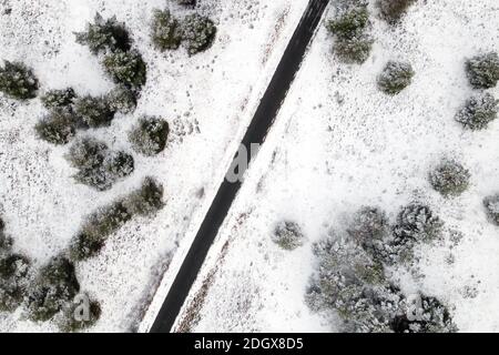 Luftaufnahme der leeren schneebedeckten Straße im Winterwald. Hochwertige Fotos. Stockfoto