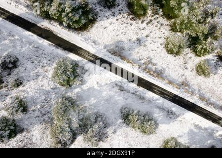 Luftaufnahme der leeren schneebedeckten Straße im Winterwald. Hochwertige Fotos. Stockfoto