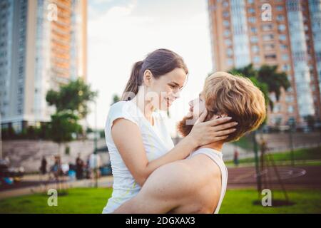 Ein junges kaukasisches Paar spielt und freut sich nach dem Training auf einer Wiese in einem Sommerpark. Das Thema der gemeinsamen Ausbildung. Gesunde Athleten Stockfoto