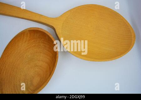 Zwei große ukrainische Holzlöffel befinden sich auf einem weißen Stoffhintergrund. Stockfoto