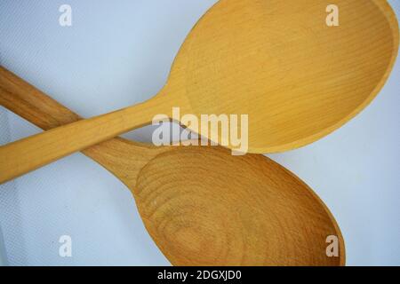 Zwei große ukrainische Holzlöffel befinden sich auf einem weißen Stoffhintergrund. Stockfoto