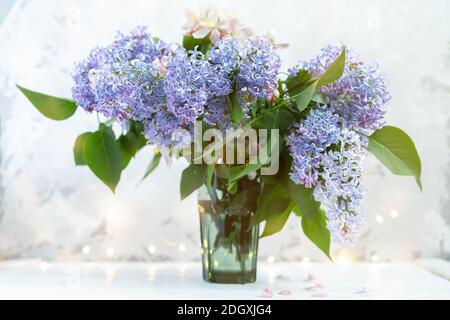 Schöne Bouquet rosa und lila Blumen auf verschwommenem weißen Hintergrund mit Lichtern. Frühling floralen Hintergrund mit Platz für Text Stockfoto