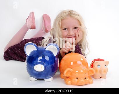 Blondes Mädchen mit 3 Sparschweine, HERR: Ja, 7 Jahre alt, Stockfoto