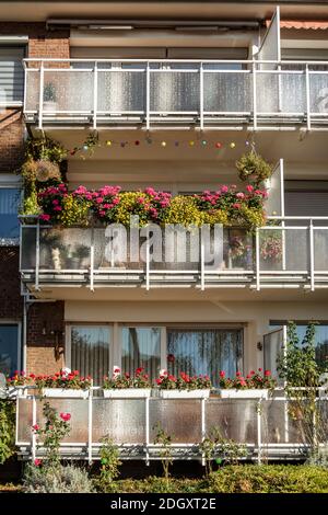 Traditionelles europäisches Wohnhaus mit Balkons mit bunten Blumen und Blumentöpfen. Fassade eines Wohnhauses mit Stockfoto