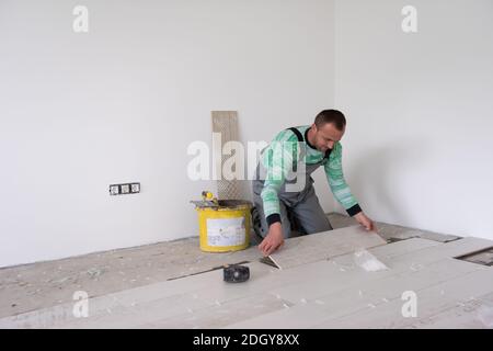 Arbeiter Installation der keramischen Holz-Effekt Fliesen auf dem Boden Stockfoto