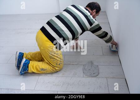 Fliesenleger füllen den Raum zwischen keramischen Holz-Effekt Fliesen Stockfoto