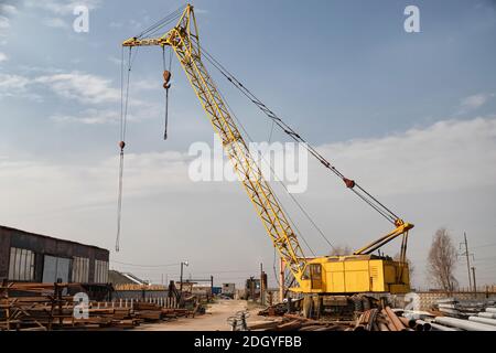 Ein großer gelber Kran steht auf der Basis von gewalzt Metall Stockfoto