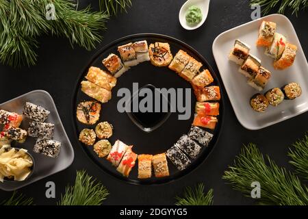 Weihnachten Brunch mit Sushi als Kranz auf schwarzem Hintergrund gesetzt. Blick von oben. Flache Lay-Optik. Weihnachten oder Silvester festliche Party. Stockfoto