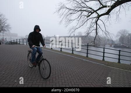 Amsterdam, Niederlande. Dezember 2020. Ein Mann fährt mit dem Fahrrad über die Brücke in der Nähe von Hermitage Museum an der Amstel während als schwere nebligen Tag mit Temperatur von 1 Grad Celsius im Vondelpark inmitten der Coronavirus-Pandemie am 9. Dezember 2020 in Amsterdam, Niederlande. Die Coronavirus-Infektionen steigen mit 6,589 neuen Menschen, die auf COVID-19 getestet heute Umfrage des öffentlichen Gesundheitsinstituts (RIVM). (Foto von Paulo Amorim/Sipa USA) Quelle: SIPA USA/Alamy Live News Stockfoto