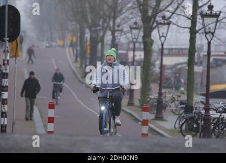 Amsterdam, Niederlande. Dezember 2020. Eine Frau fährt am 9. Dezember 2020 in Amsterdam, Niederlande, während eines schweren nebligen Tages mit einer Temperatur von 1 Grad Celsius an der Amstel, inmitten der Coronavirus-Pandemie, Fahrrad auf der Walter-Suskind-Brücke. Die Coronavirus-Infektionen steigen mit 6,589 neuen Menschen, die auf COVID-19 getestet heute Umfrage des öffentlichen Gesundheitsinstituts (RIVM). (Foto von Paulo Amorim/Sipa USA) Quelle: SIPA USA/Alamy Live News Stockfoto