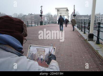 Amsterdam, Niederlande. Dezember 2020. Ein Künstler malt die Szene auf der alten hölzernen Magere-Zugbrücke über die Amstel während eines schweren nebligen Tages mit einer Temperatur von 1 Grad Celsius im Vondelpark inmitten der Coronavirus-Pandemie am 9. Dezember 2020 in Amsterdam, Niederlande. Die Coronavirus-Infektionen steigen mit 6,589 neuen Menschen, die auf COVID-19 getestet heute Umfrage des öffentlichen Gesundheitsinstituts (RIVM). (Foto von Paulo Amorim/Sipa USA) Quelle: SIPA USA/Alamy Live News Stockfoto