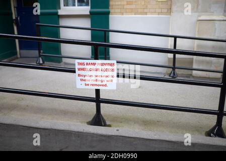 London, England, Großbritannien. Rollstuhlrampe in Covent Garced, mit Warnschild gegen Verkettung Fahrräder an das Geländer Stockfoto