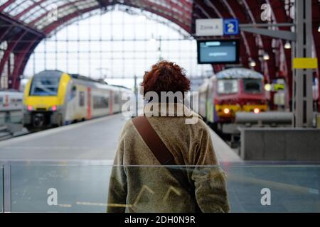 Rückansicht einer Frau, die auf dem Bahnsteig des Bahnhofs steht Stockfoto