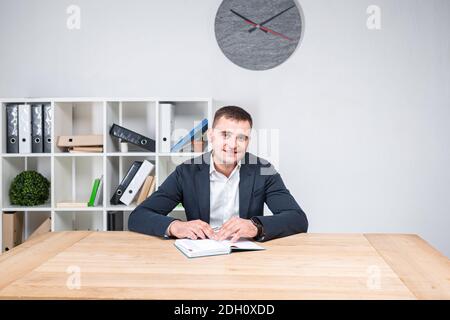 Portrait eines kaukasischen Mannes in Innenräumen posiert in einer Jacke und weißem Hemd. Übergewichtige Büroangestellte am Arbeitsplatz. Das Thema von Stockfoto